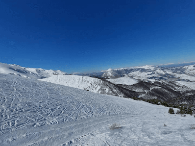 A scenic winter view in Brezovica Kosovo showcasing a bustling ski resort. A skier navigates snowy slopes near a cozy challet. The surroundings resonate with vibes of winter sports.