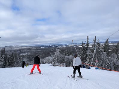 Winter scene at Poley Mountain ski resort in Waterford, New Brunswick, Canada featuring a ski lift and skiers enjoying the slopes.