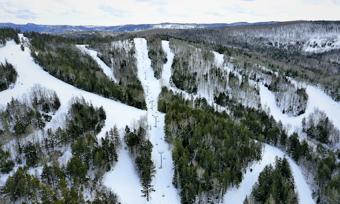 Ski resort at Poley Mountain in Canada featuring a wintery scene with a ski lift, snow-covered slopes, skiers enjoying winter sports.