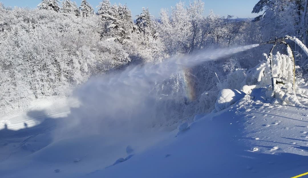 Winter sports scene at Mont Ste-Marie ski resort in Quebec, Canada, showcasing the beautiful winter landscape and a snowmobile in the distance. Perfect destination for ski lovers.