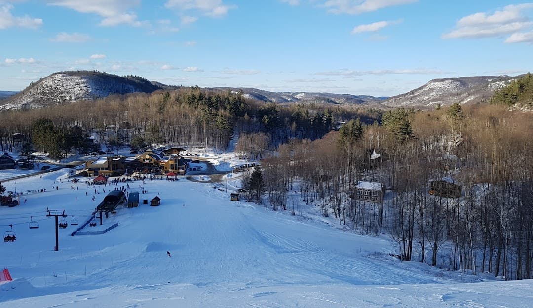 Winter sports enthusiasts enjoying a snowy day at Mont Ste-Marie ski resort in Quebec, Canada, complemented by a beautiful winter scenery and a ski lift.