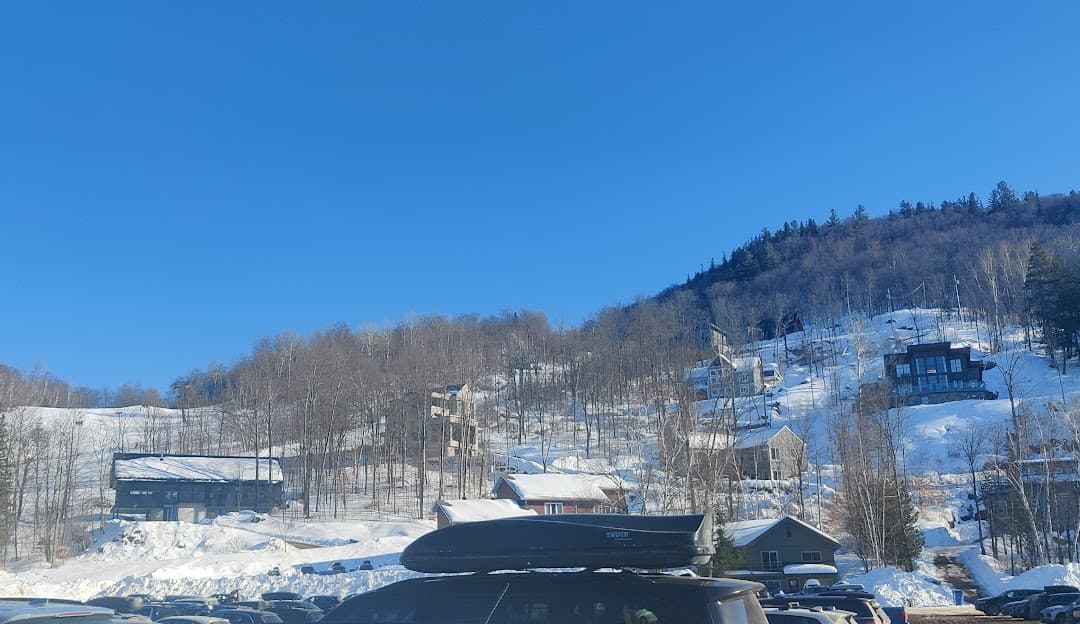 A picturesque winter scene at Mont Ste-Marie ski resort in Quebec, Canada featuring a charming chalet, prime winter sports facilities, set against breathtaking snowy scenery.