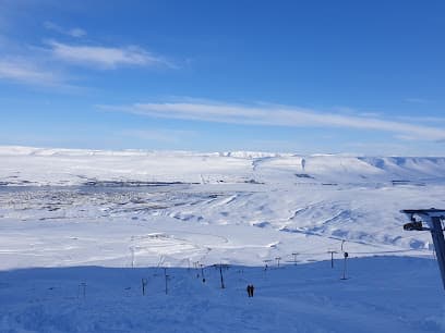 Winter sports scene at Hlíðarfjall ski resort in Akureyri, Northeast Iceland, featuring a challet and picturesque snow-covered slopes.