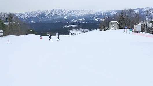 A family enjoying a day of skiing at a resort in Tainai Chūbu Japan. The scenic snowy alpine backdrop enhances the joyous winter sports scene.