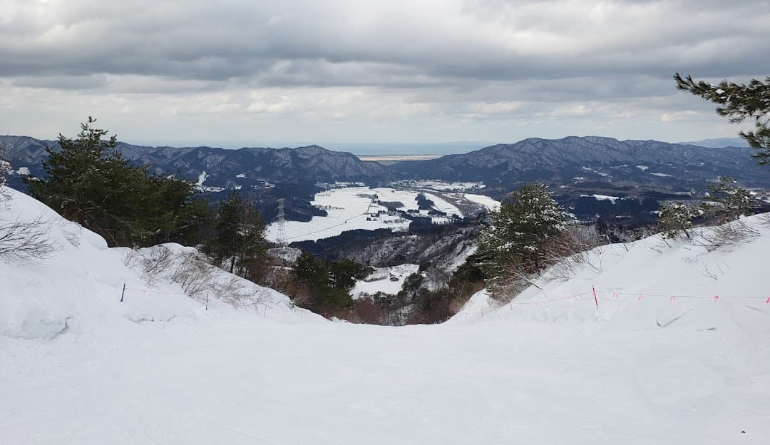 A stunning winter scene in Tainai, Japan featuring a scenic winter sports scene at a ski resort. The picturesque backdrop includes a snow-covered mountain.