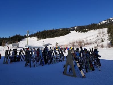 Winter scene at Murray Ridge in British Columbia, Canada showcasing a bustling ski resort with multiple skiers enjoying the slopes. A ski lift transports skiers uphill, enhancing the beautiful snowy scenery.