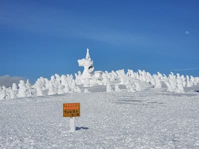 Winter scene at Hakkoda, Japan, showcasing a serene snowy landscape. Skiers descend a mountain slope in a popular ski resort, highlighting the allure of winter sports in the scenic, snow-laden terrain.