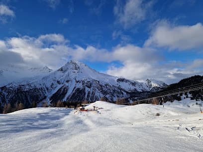 Winter scene at Skigebiet und Minschuns ski resort in Graubünden, Switzerland, featuring skiing trails, a charming chalet, and a magnificent mountain backdrop.
