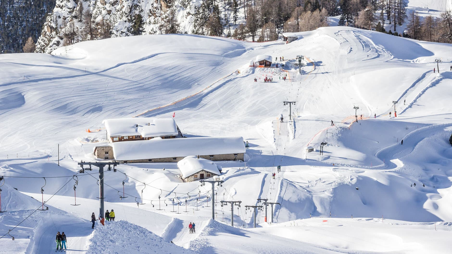 Winter scene at Skigebiet und Minschuns ski resort in Eastern Switzerland, featuring skiers enjoying the snow-covered slopes, with a ski lift visible in the background.