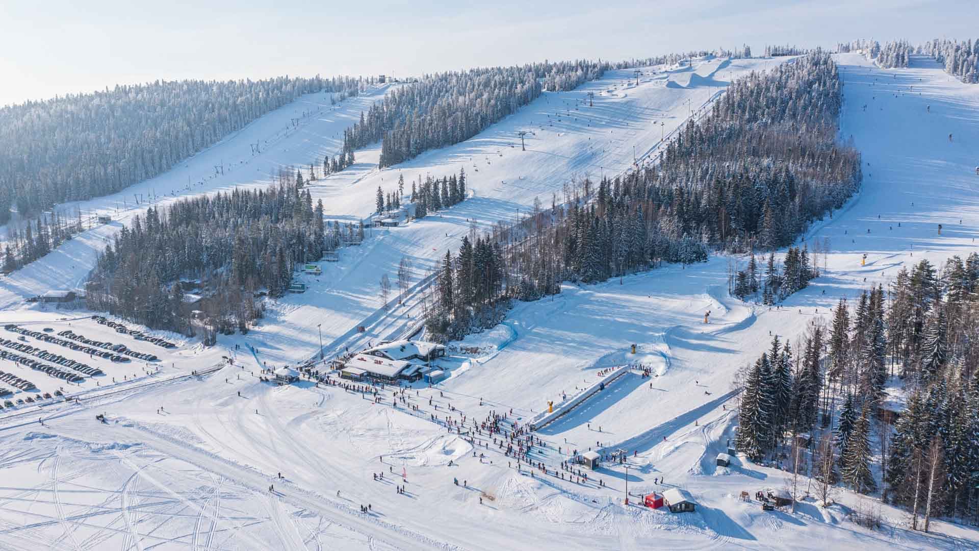 A winter sports scene at Tahko ski resort in Kuopio Finland featuring a ski lift and a distant skier enjoying the snow-covered slopes.