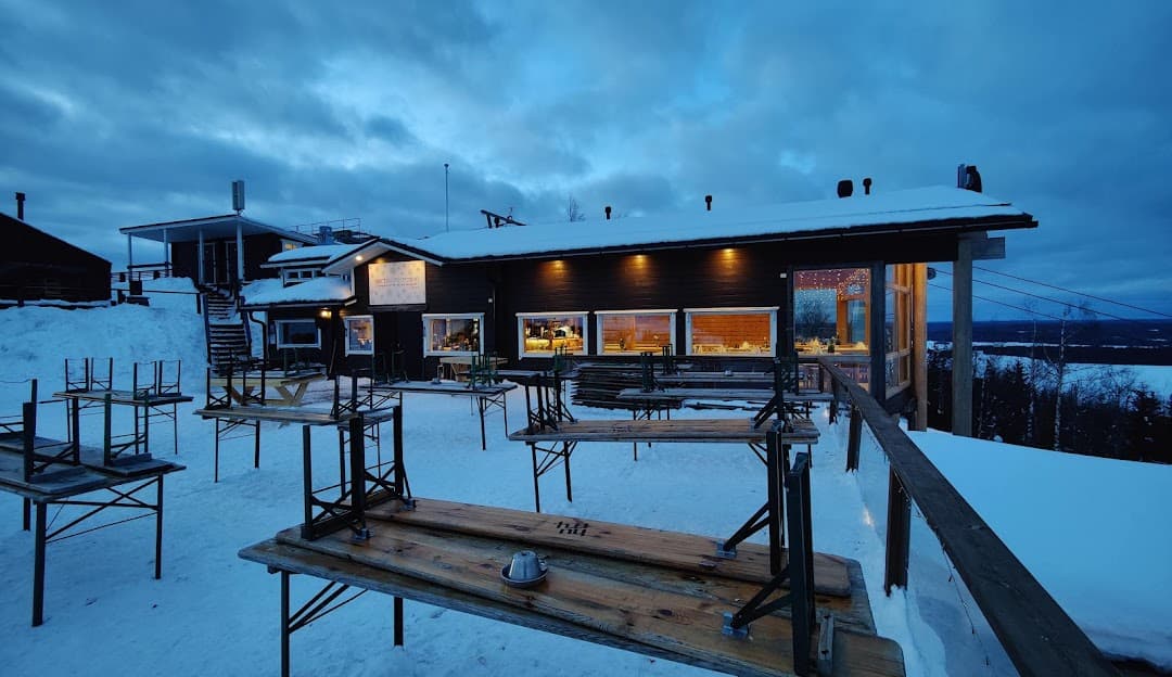 Winter scene at Tahko ski resort in Finland, featuring a sports centre and a cozy chalet amongst a snow-covered landscape.