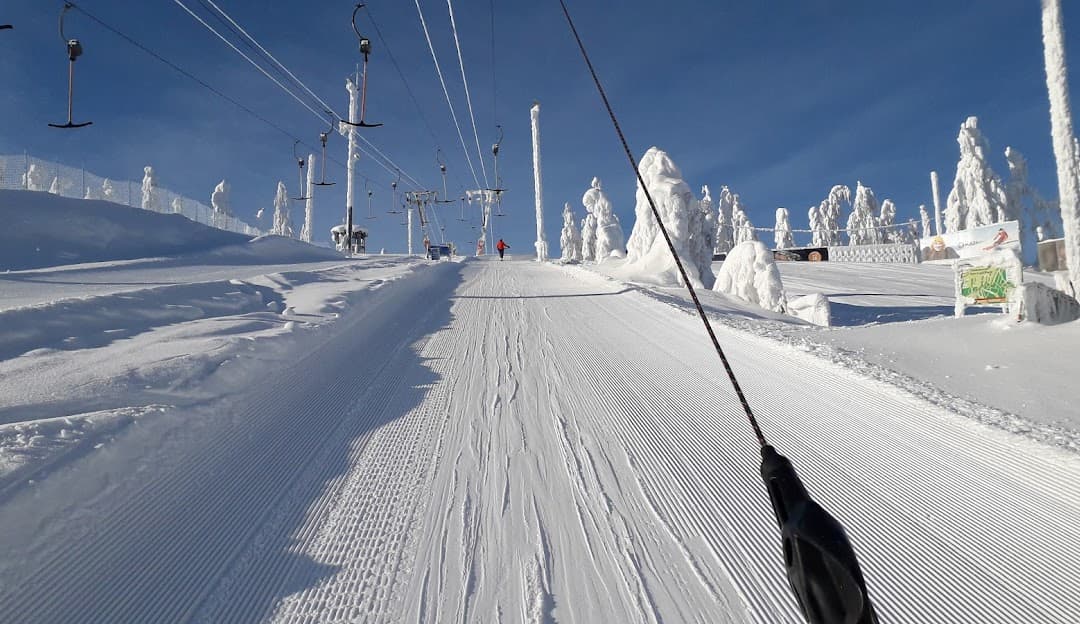Ski lift and a skier poised to descend at the snow-drenched Tahko ski resort, Kuopio, Northern Savonia, East Finland, showcasing a lively winter sports scene.