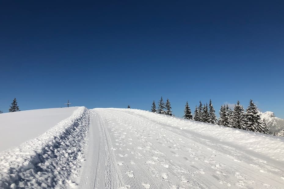 Winter scene at Krinnenalpe, Reutte, Austria showcasing a bustling ski resort. Ski enthusiasts glide down snow-covered slopes with a scenic chalet nestled amidst stunning winter scenery.