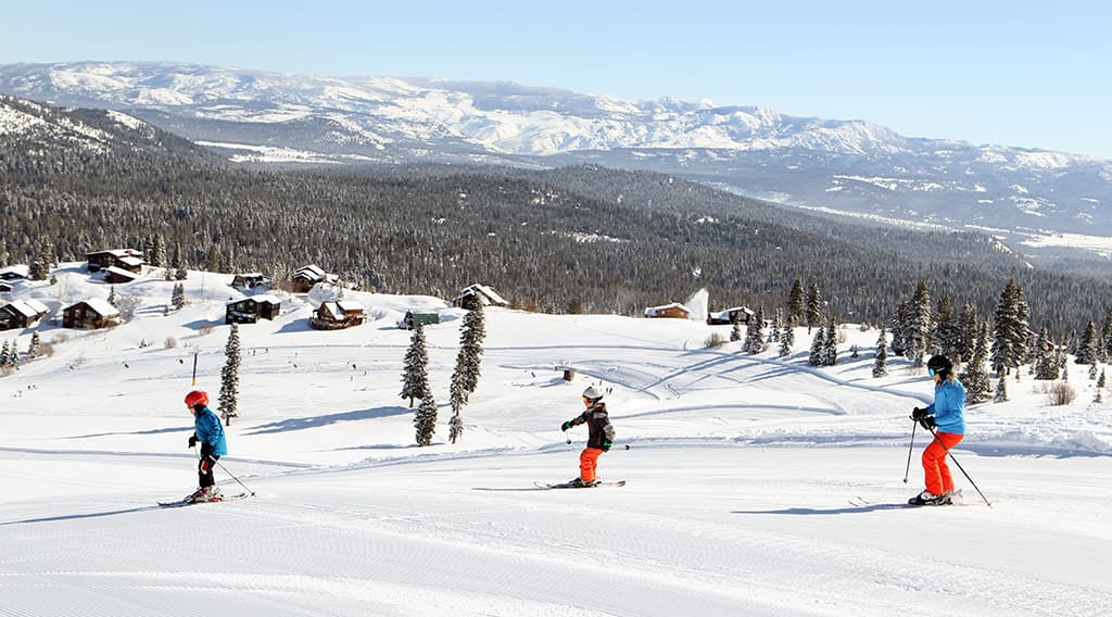 A lively winter sports scene at Tahoe Donner ski resort in Truckee California featuring skiers and a snowboarder gliding down the snow-covered slopes.