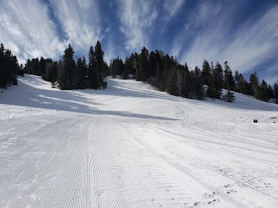 A skier gliding down snow-covered slopes at a ski resort in Cloudcroft New Mexico with a charming chalet in the background amidst a bustling winter sports scene.