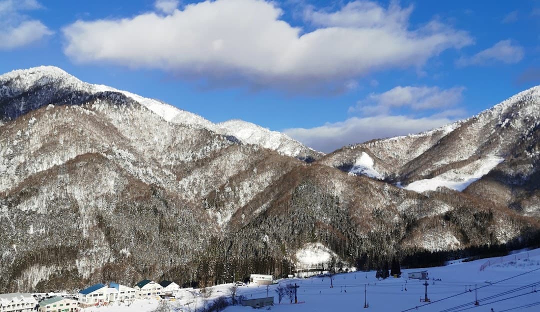 Winter scene at Honokidaira in Chūbu, Japan featuring snow-covered mountain ranges and a ski resort, encapsulating a stunning winter sports atmosphere.