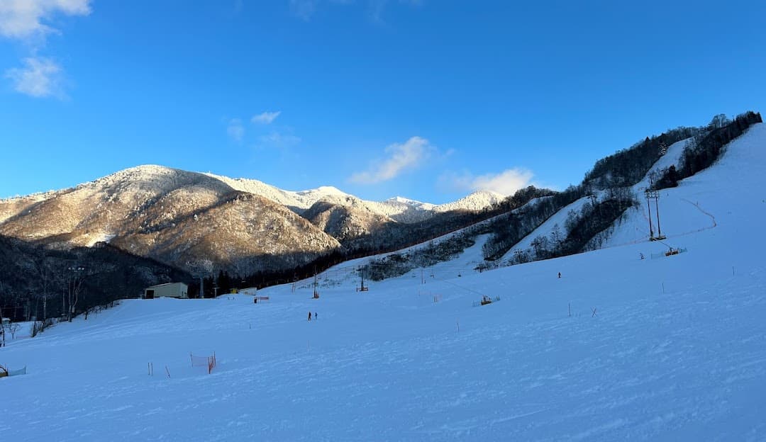 A winter sports scene unfolds at Honokidaira, Takayama, Japan with a charming chalet overlooking a stunning snow-covered landscape, indicative of a ski resort.