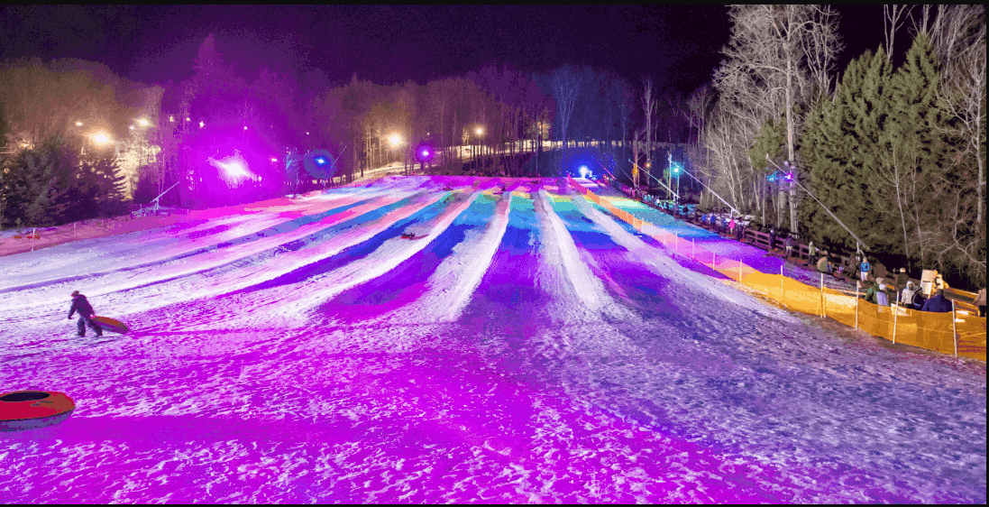 Winter scene at Peek n Peak, New York, featuring snow-covered slopes busy with winter sports, a snowmobile and a chalet nestled in the stunning snowy landscape. Leisurely activities at a winter sports centre.