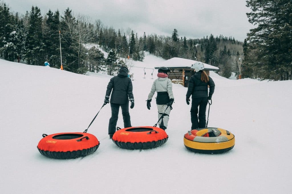 A family enjoying skiing at Sugarloaf Provincial Park in Atholville New Brunswick with a visible ski lift and winter sports facilities in the beautiful Canadian snow.