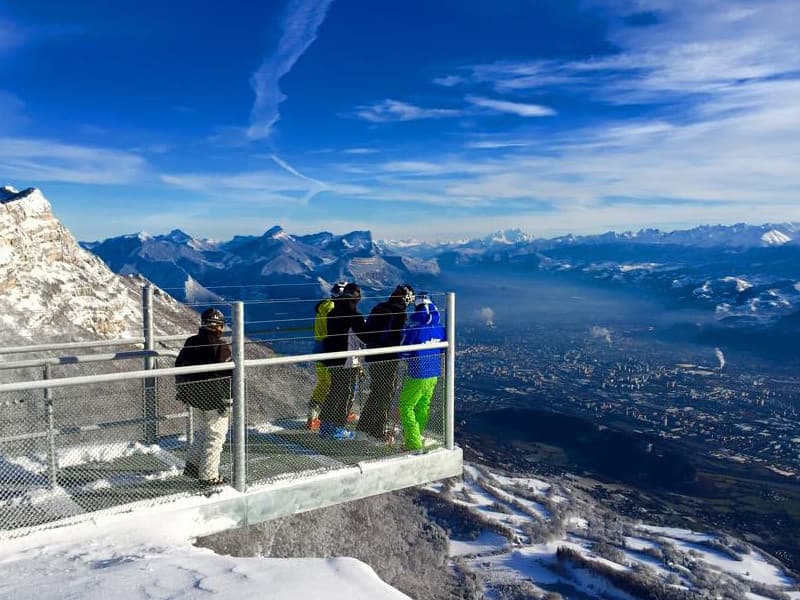 A scenic winter view in Lans en Vercors France featuring a chalet and a mountain backdrop. A family is enjoying skiing at the local ski resort.