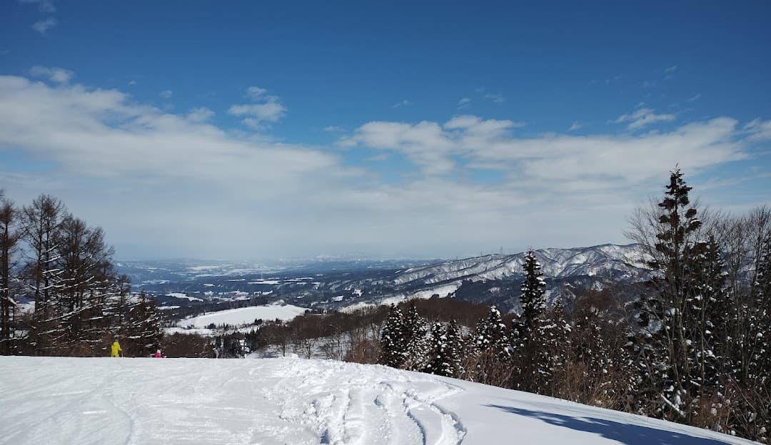 A picturesque winter scene at Greenpia Tsunan ski resort in Japan showing the stunning snowy terrain of the ski slopes a quaint chalet and breathtaking winter scenery.