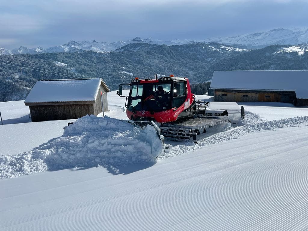 A snowmobile parked near a charming chalet amidst a bustling winter sports scene at Brunni-Bahnen, a ski resort in Engelberg-Titlis, Central Switzerland.