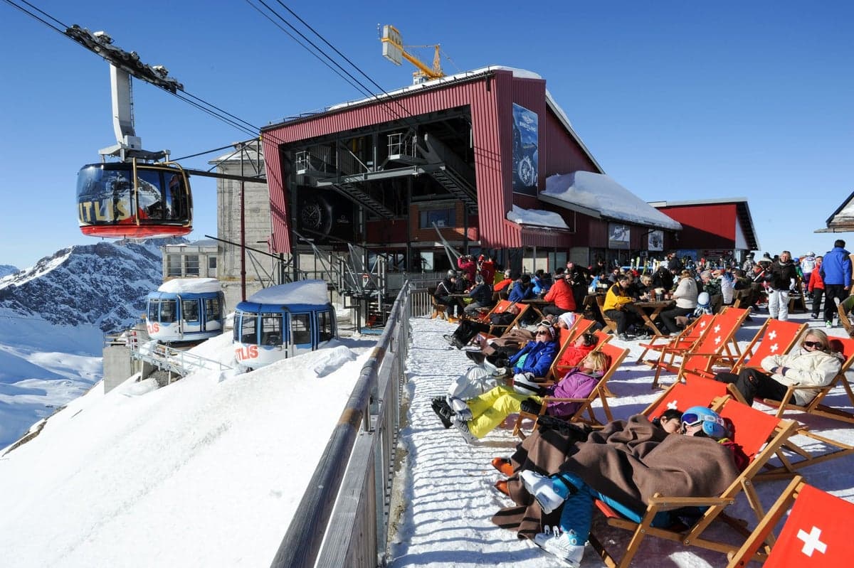 Brunni-Bahnen - Die Sonnenseite von Engelberg in Switzerland - a group of people sitting on top of a snow covered slope.