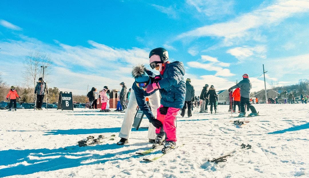 Winter scene at Bousquet ski resort in Pittsfield, Massachusetts, featuring a family enjoying a day of skiing, with a child learning to ski.