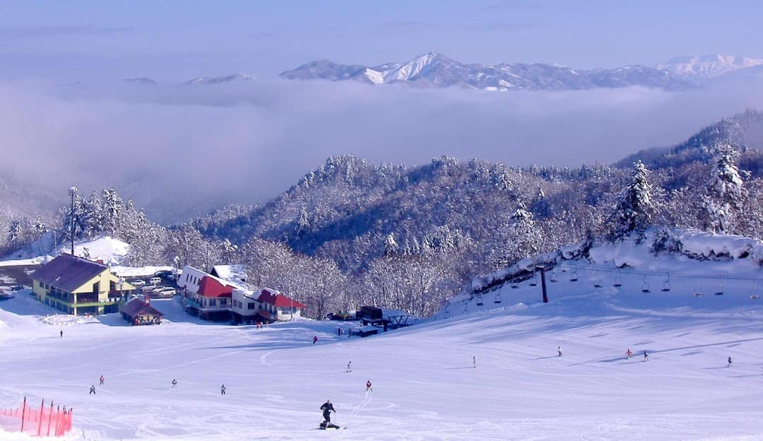Winter scene at Hida Kawai, Japan, featuring a bustling ski resort with a chalet amidst stunning snowy surroundings, serving as a hub for winter sports enthusiasts.