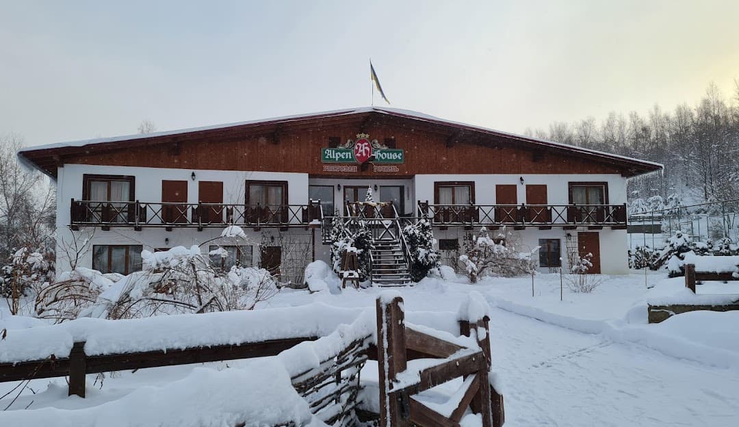 Winter scene at Krasiya in Vyshka, Ukraine highlighting a bustling winter sports centre, a cosy lodge and chalet amidst a snowy ski resort landscape.