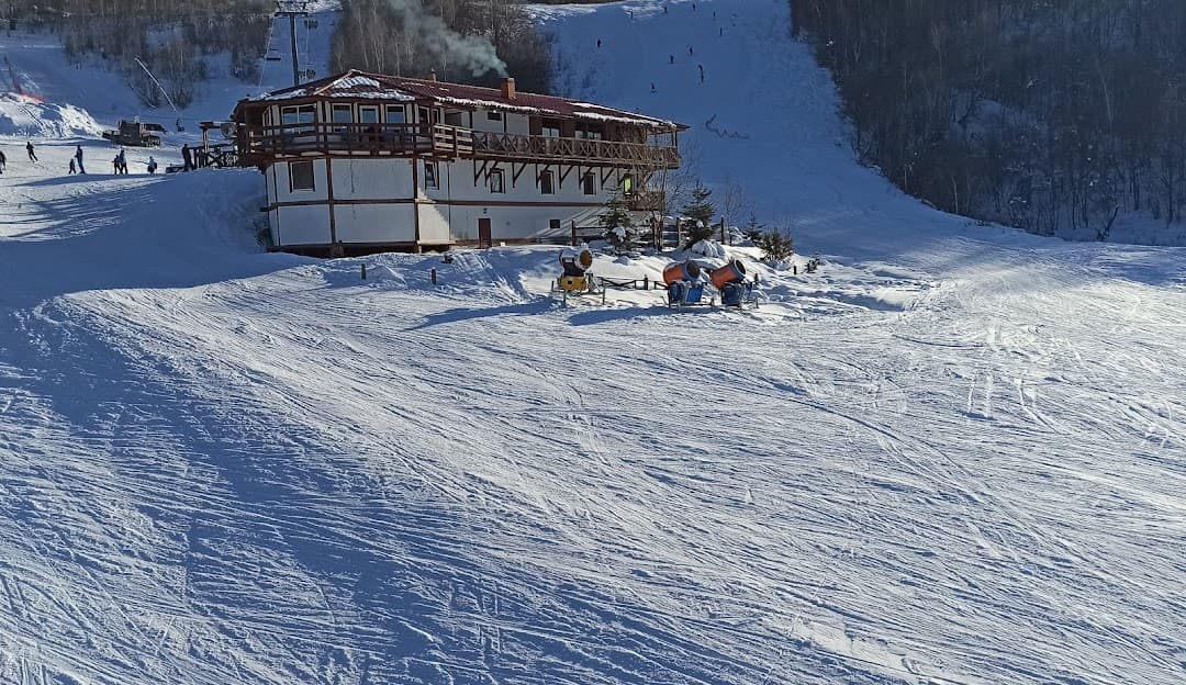 Ski resort in Krasiya, Vyshka, Ukraine featuring an active ski lift leading up to a cozy chalet. The area is bustling with winter sports activities.