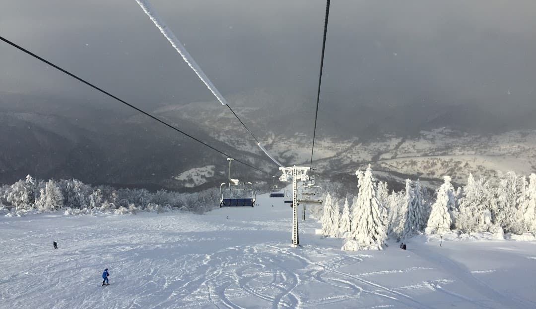 Ski lift and resort at Krasiya in Vyshka, Zakarpattia, Ukraine bustling with winter activities. A skier is descending the snowy slopes near a cozy challet.