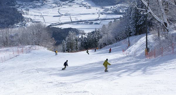 Winter sports scene at Megahiraonsen Megahira Ski Area, Hiroshima, Japan, featuring a ski resort, a winter sports centre, a chalet, and a skier enjoying the snowy slopes.