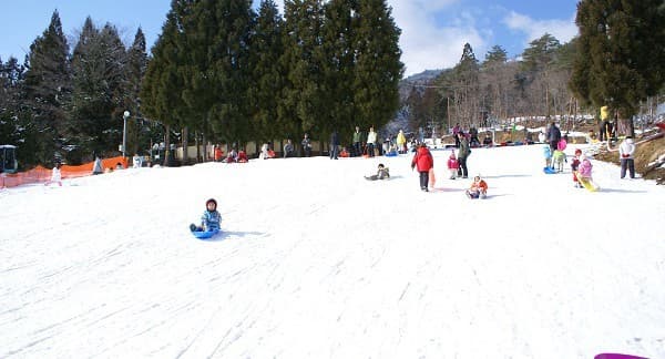 Winter sports scene at Megahiraonsen Megahira Ski Area in Hiroshima, Japan, featuring a bustling ski resort, a charming chalet, and a ski lift.