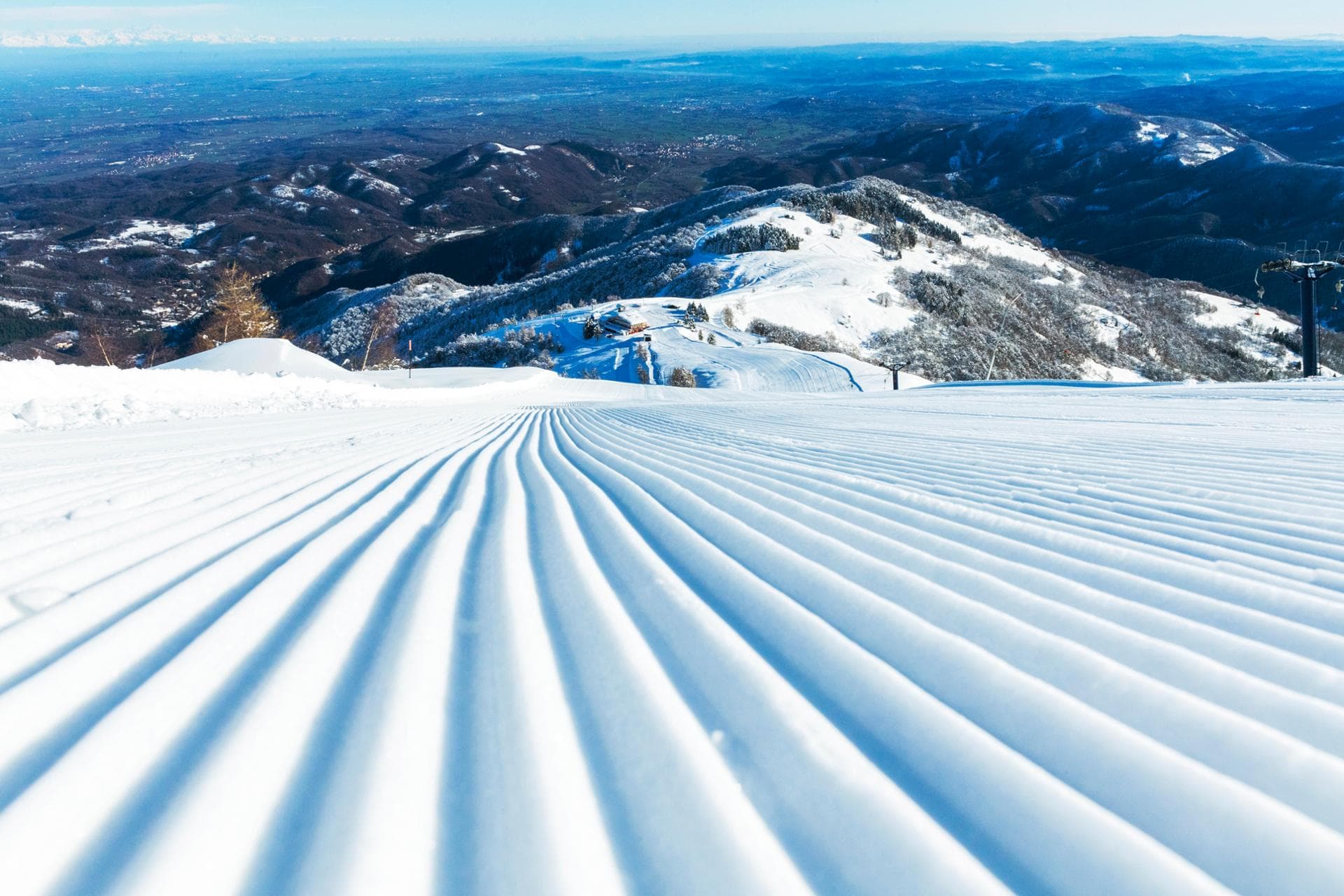 A skier carving down the snow-covered slopes at Lurisia Monte Pigna a ski resort in Italy. Breathtaking winter scenery in the background completes this dynamic winter sports image.