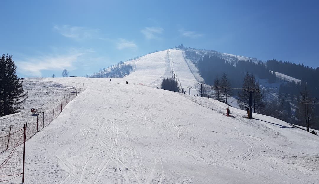 A scenic winter view at the Lurisia Monte Pigna ski resort in Italy featuring a charming chalet a skier navigating snow-covered slopes and bustling winter sports activities.