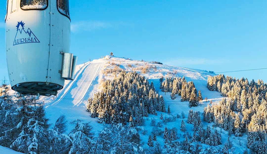 View of Lurisia Monte Pigna ski resort in Piedmont Italy. Features a chalet ski lift and the winter sports centre amidst the stunning winter scenery.
