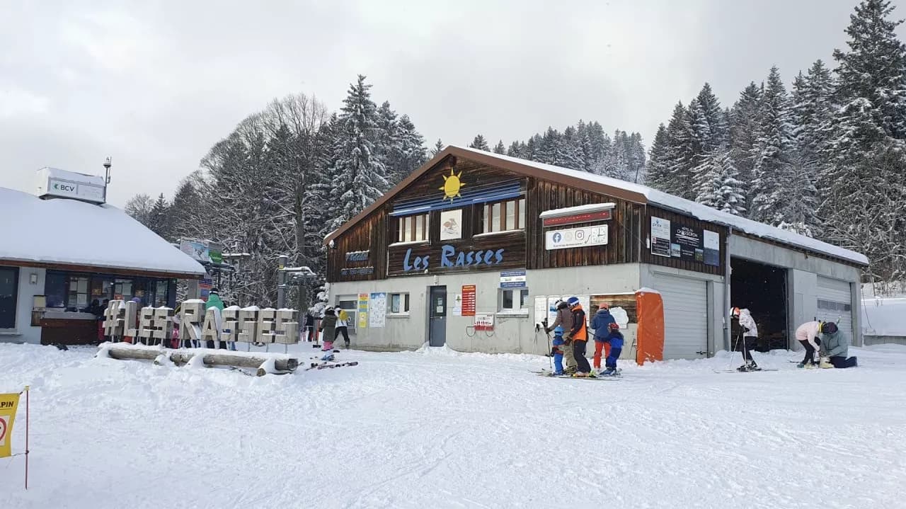 Winter view of Ste-Croix - Les Rasses in Switzerland, featuring a bustling winter sports centre amidst a serene ski resort, dotted with the occasional chalet.