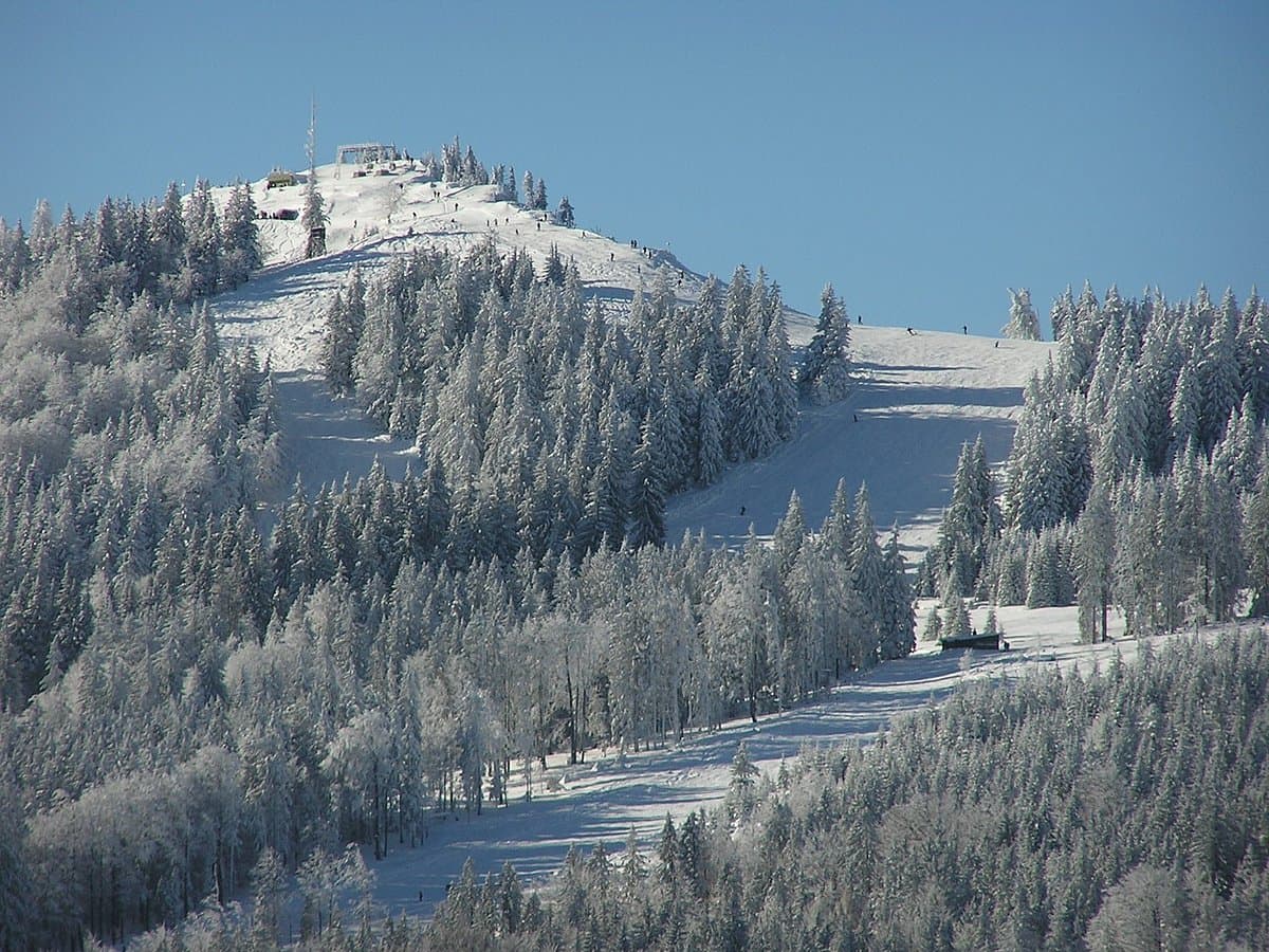 A scenic view from Unterberg in Wiener Alpen Austria showcasing a popular ski resort. Snow-covered slopes and a ski lift set a perfect stage for winter sports in this wintry panorama.