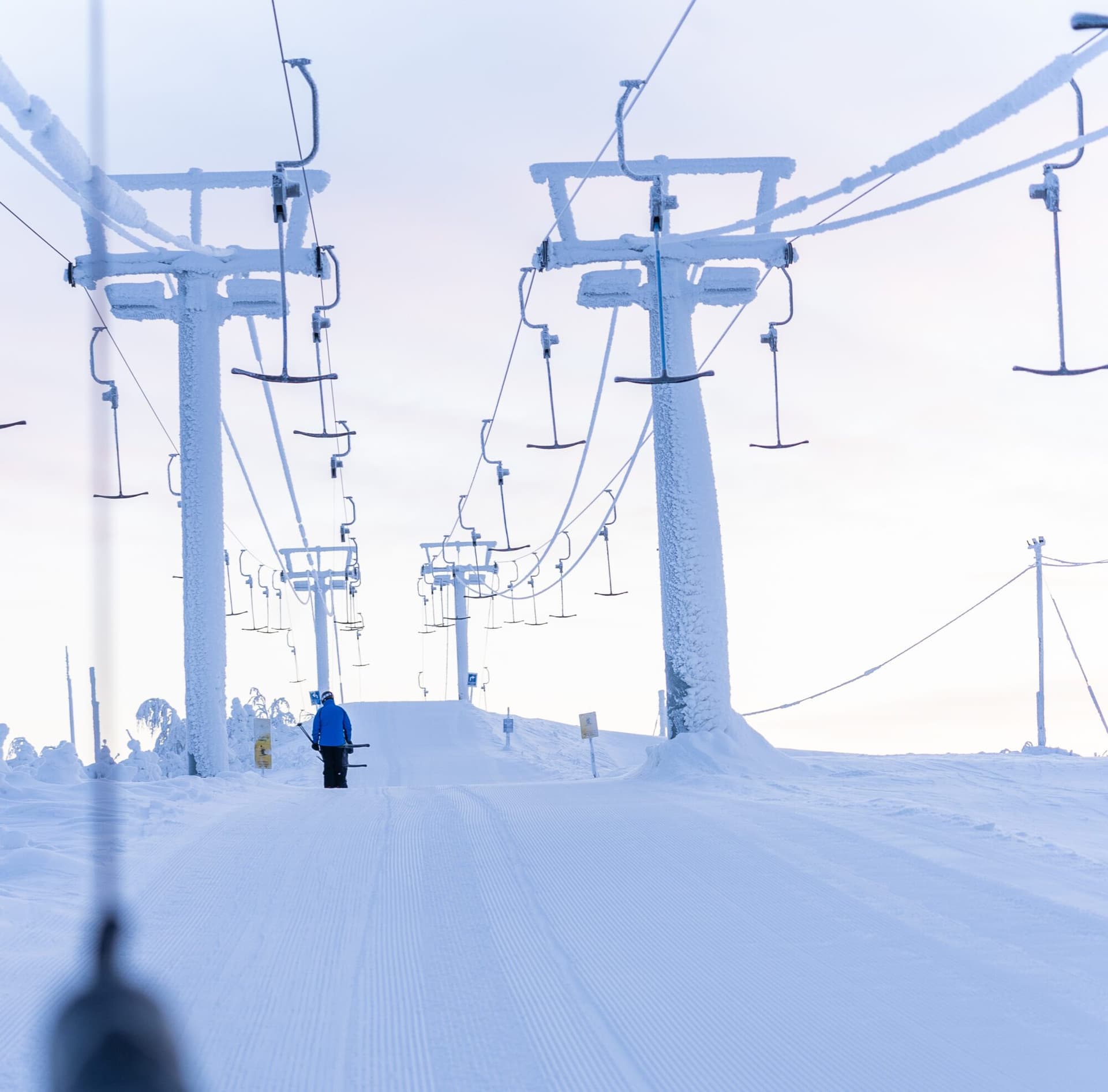 Winter sports scene at Ukkohalla, Kainuu, featuring a ski lift, a skier enjoying the slopes, and a stunning winter landscape in the backdrop of a ski resort.
