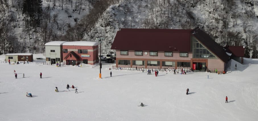 Winter scene at Taira, Japan, featuring a bustling sports centre and ski resort, complete with a quaint chalet, amidst stunning winter scenery.