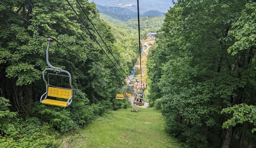 View of Ober Mountain in Gatlinburg Tennessee featuring a ski lift prominently with a hint of a ski resort and chalet amidst the pristine snowy terrain.