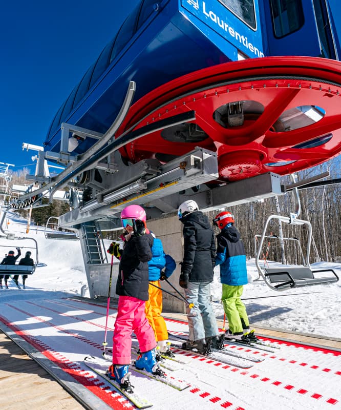 A ski lift operates at the vibrant Sommet Gabriel ski resort in Quebec Canada brimming with winter sports enthusiasts. A family enjoys skiing together creating lifetime memories.