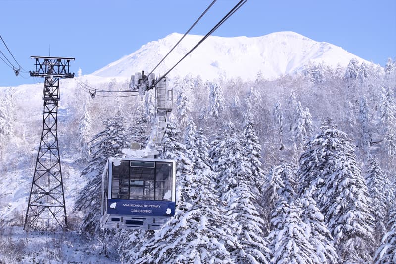 Asahidake in Japan - the sun is shining through the clouds over a snowy landscape.