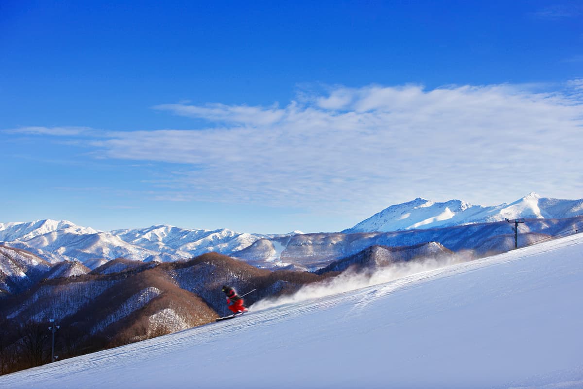 Okutone Snow Park in Japan - a person riding a snowboard down a snowy slope.