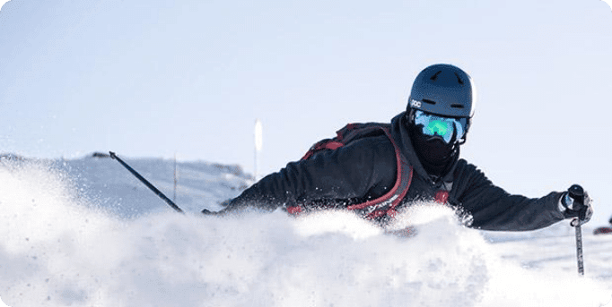 A skier in action at Peyragudes, Hautes-Pyrénées, Occitanie, France. The winter sports scene is set against a backdrop of a chalet and snowboarders are also present.