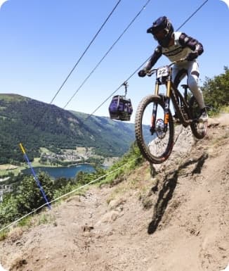 A mountain biker enjoys a ride in the beautiful terrain of Peyragudes in Hautes-Pyrénées France with a quaint chalet visible in the backdrop.