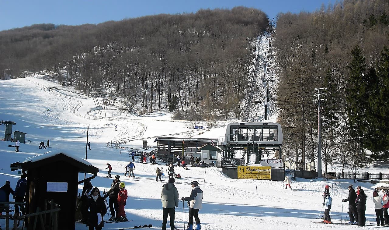 Seggiovia di Caldirola in Italy - a group of people skiing down a snowy slope.