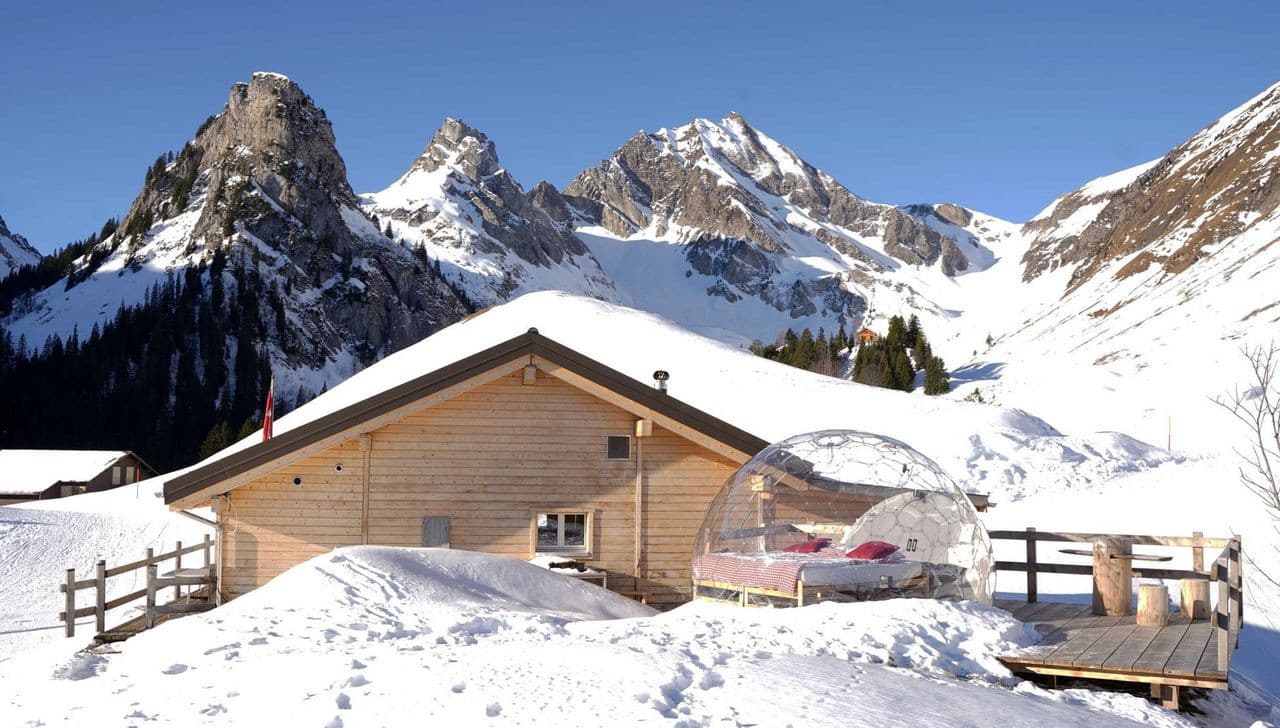 Gitschenen in Switzerland - a snow covered cabin with mountains in the background.