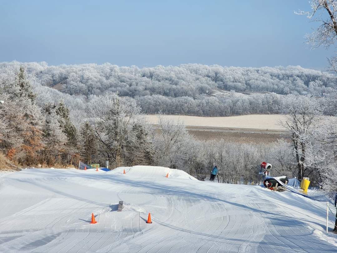 A skier enjoying winter sports at the winter sports centre in Seven Oaks, Iowa, surrounded by stunning scenery covered in pristine white snow.
